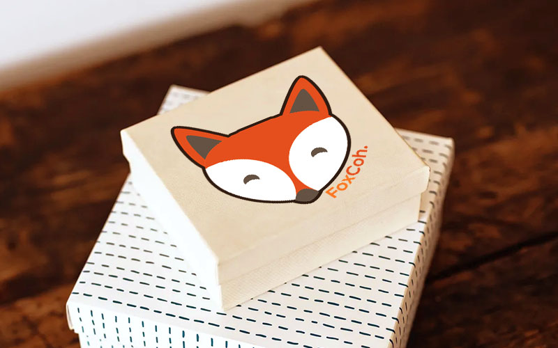 Coffret FoxCoh en carton clair marqué du logo renard, posé sur une table en bois.